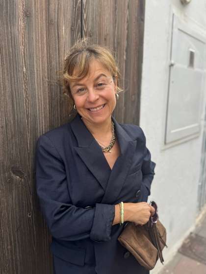 Lea Wernli im dunkelblauen Blazer, lacht, lehnt an einer Holzwand